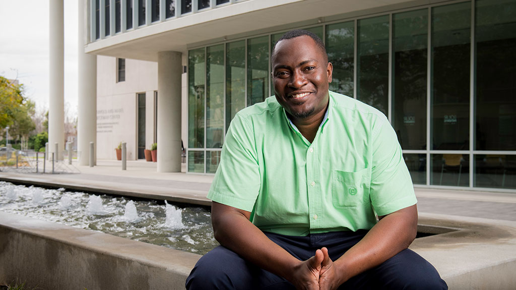 Chris Sistrunk sitting and smiling by a fountain