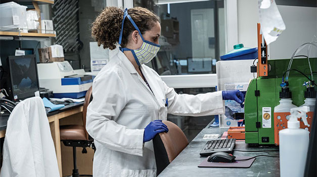 Researcher standing at desk interacting with equipment