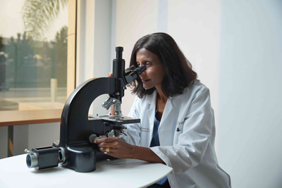Amrita Krishnan, M.D. using microscope