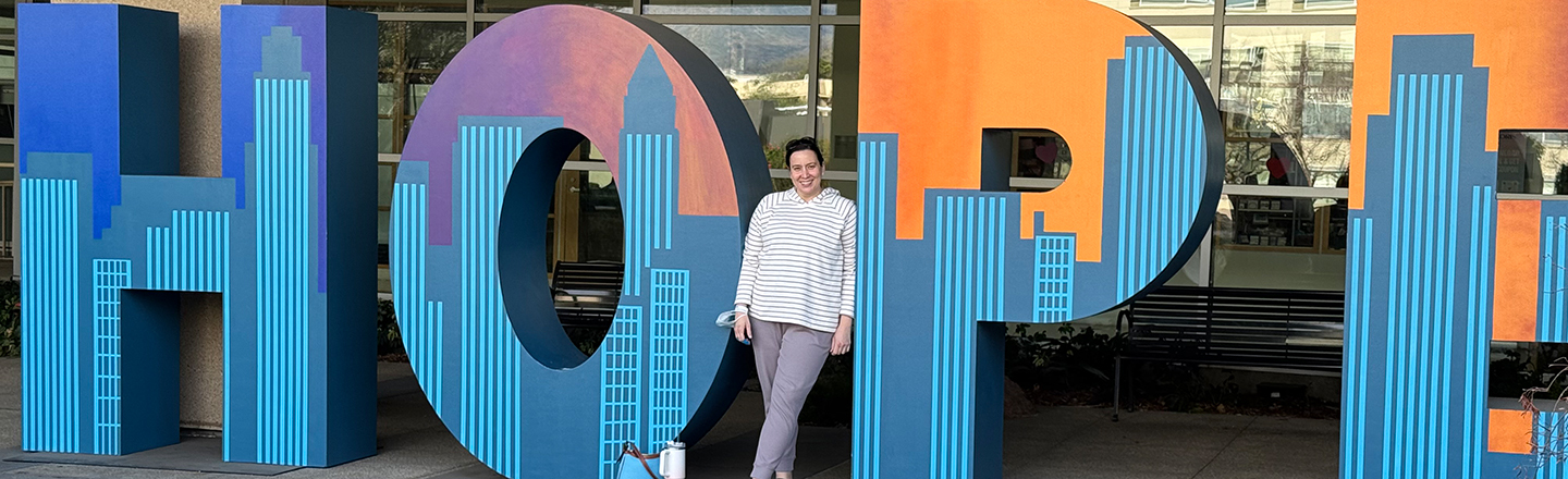 Young woman standing a smiling next to HOPE letters