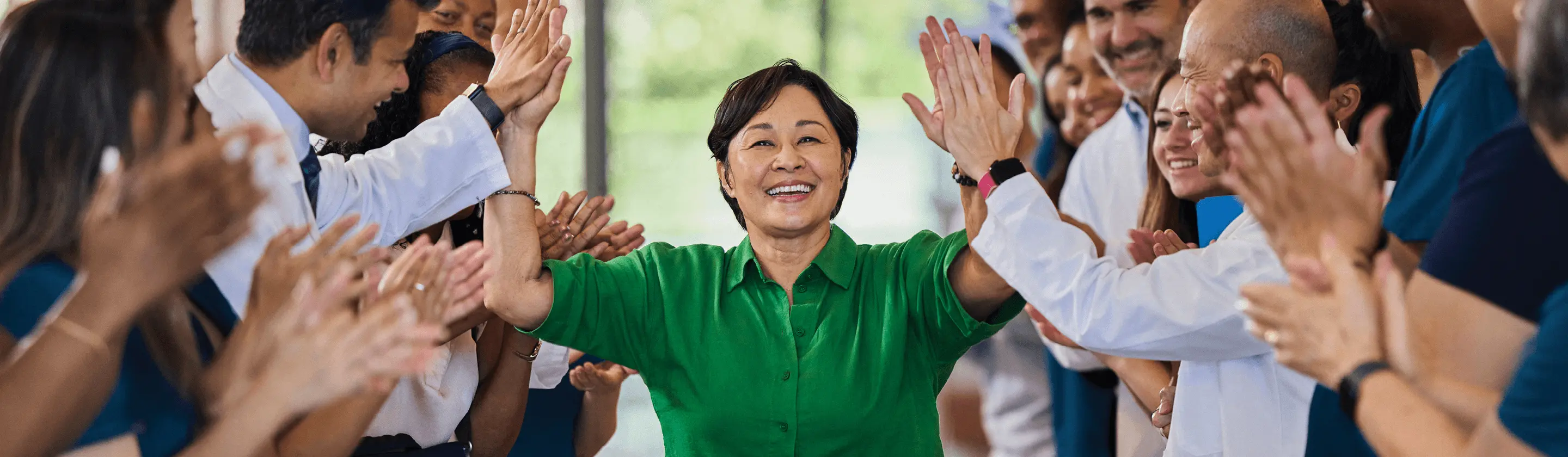 A patient is high-fiving their care team as they walk down the hospital hallway.
