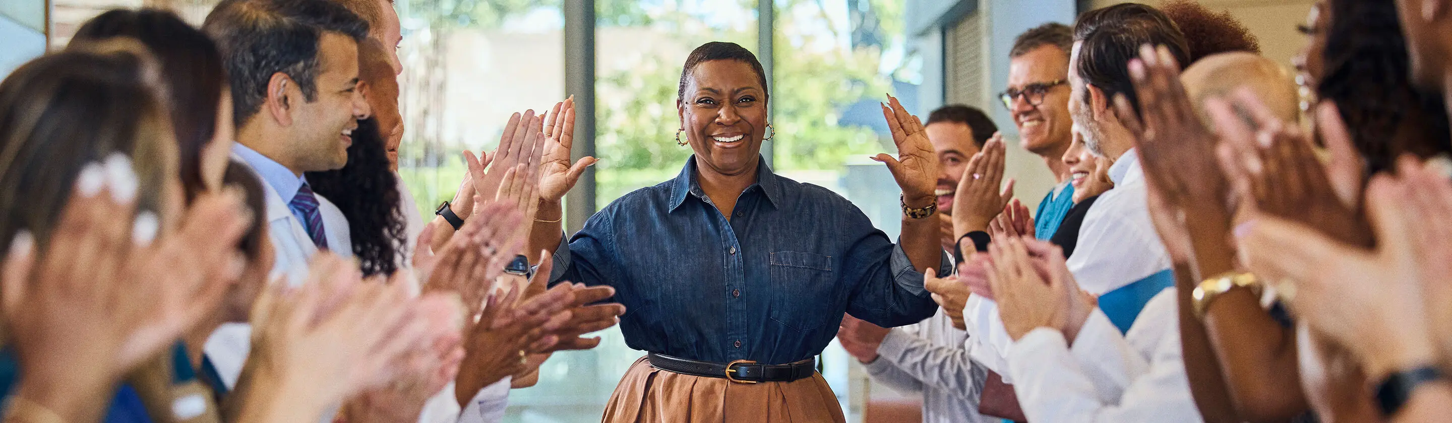 A patient is high-fiving their care team as they walk down the hospital hallway.