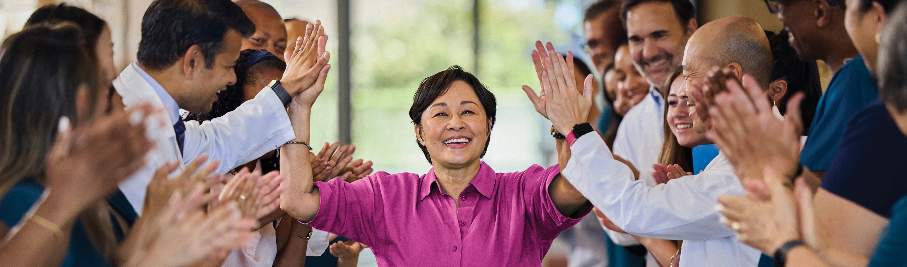 A patient is high-fiving their care team as they walk down the hospital hallway.