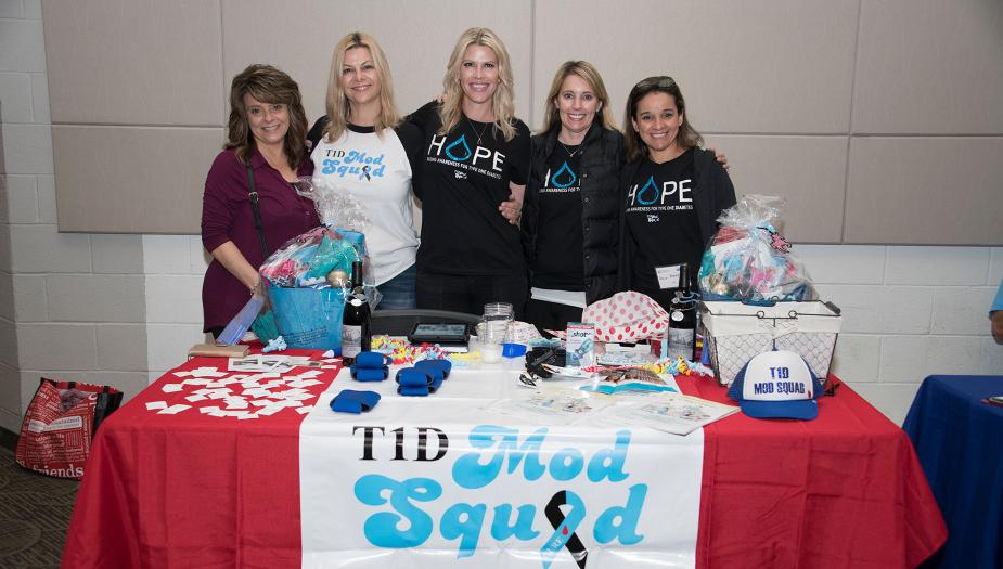 Four people standing behind a T1D Mod Squad promotion table