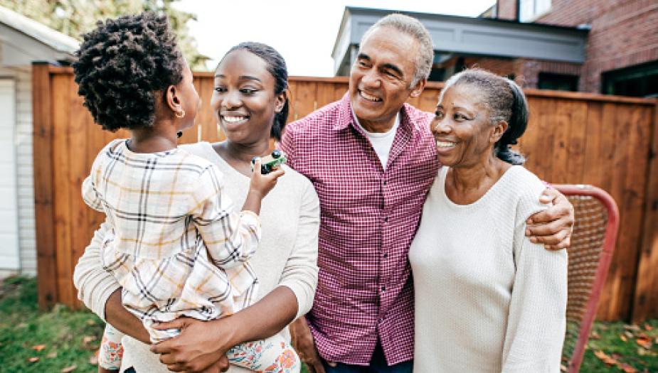 grandparents smiling at child who is in mom's arms