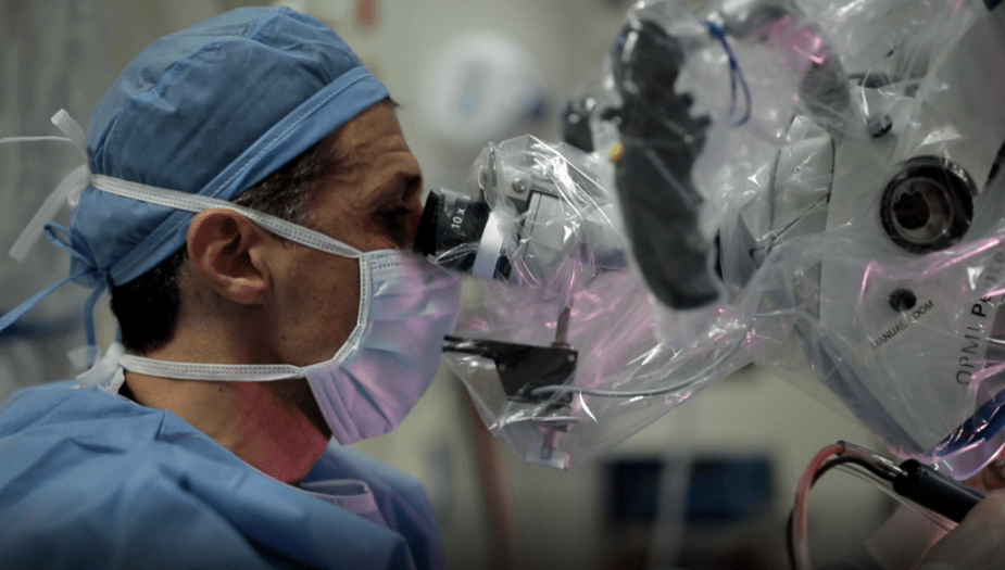 a masked up surgeon looking into the scope