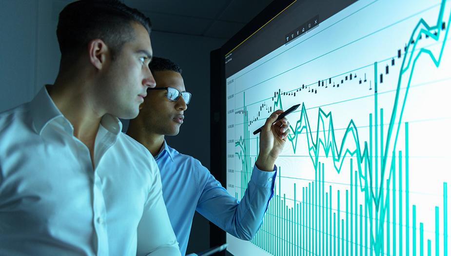 Two businessmen studying graphs on an interactive screen