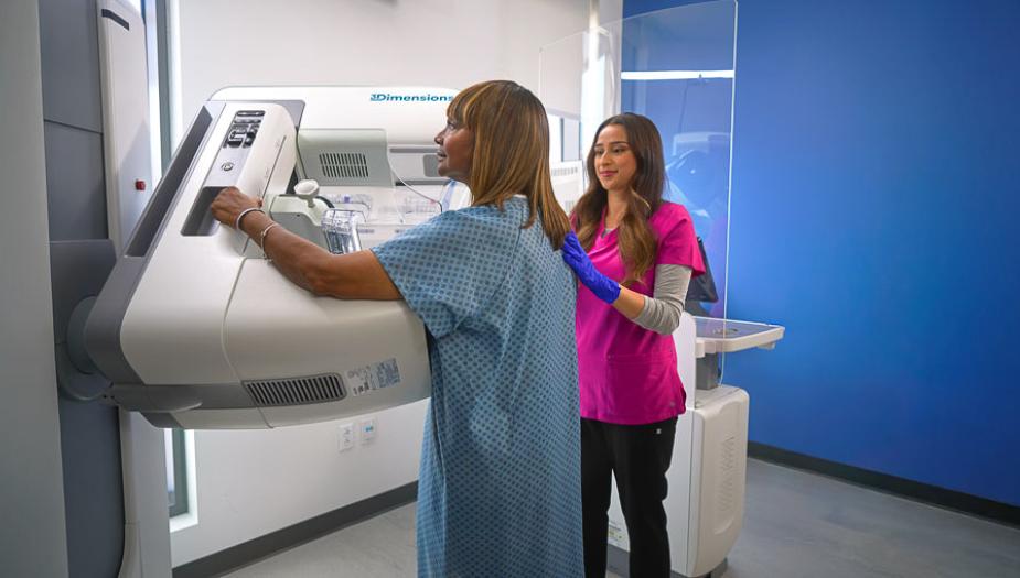 A patient getting a mammogram and being assisted by a nurse