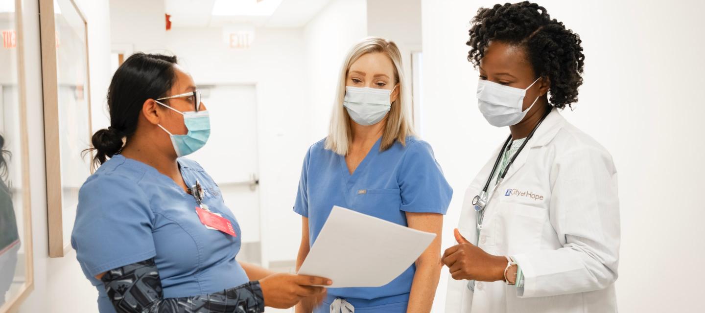 A doctor talking with two nurses about a report