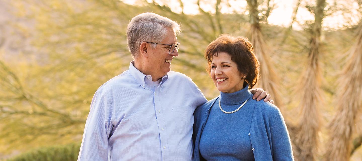 Photo of A. Emmet Stephenson Jr. hugging his late wife, Toni, as they walk along a nature trail.