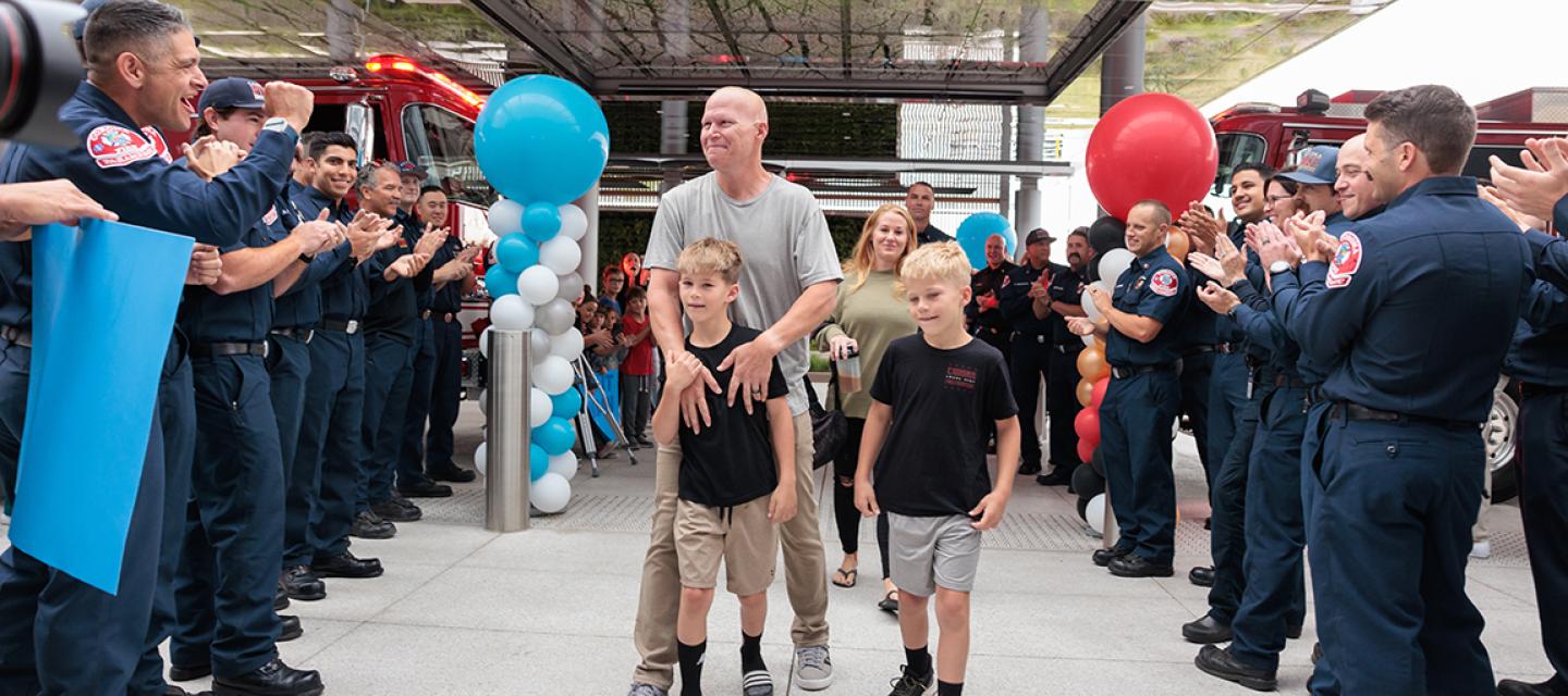 Brandon Willson, his sons Gavin and Luke, and wife Amber walk through dozens of firefighters as they show their support for the battalion chief