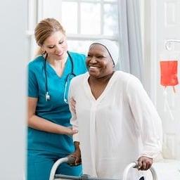 Nurse assists cancer patient with walker