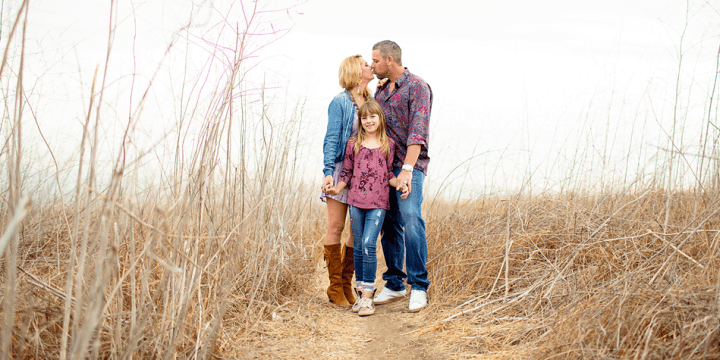 Gary Heyer and wife kissing while holding their daughter