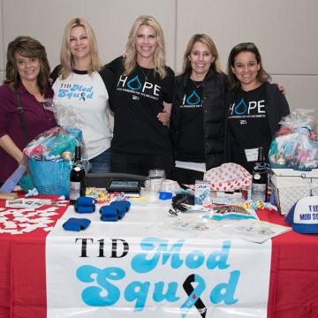 Four people standing behind a T1D Mod Squad promotion table