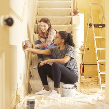 Two women doing home repairs