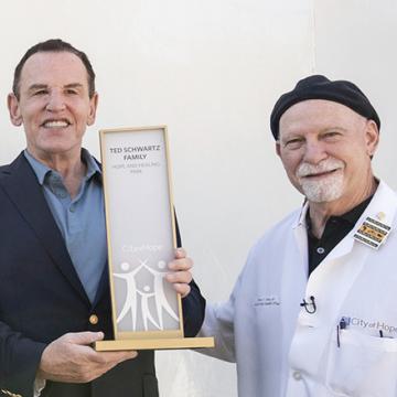 Ted Schwartz with Steven Rosen, M.D., while holding a plaque of recognition for the Ted Schwartz Family gift