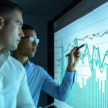 Two businessmen studying graphs on an interactive screen