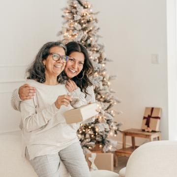 Caregiver and patient hugging in front of a Christmas tree