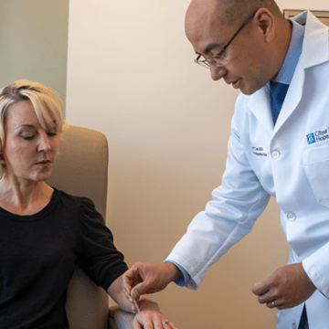Richard T. Lee, M.D., Cherng Family Director’s Chair for the Center for Integrative Oncology, places a needle for acupuncture treatment onto a patient’s arm.