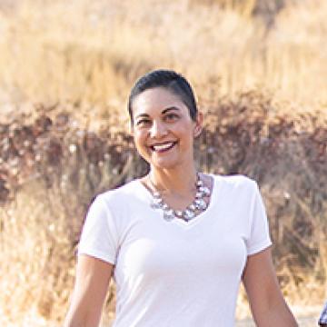 Triumphant smile of Natasha Shows, a City of Hope of breast cancer survivor, standing in a in a wildflower-filled meadow