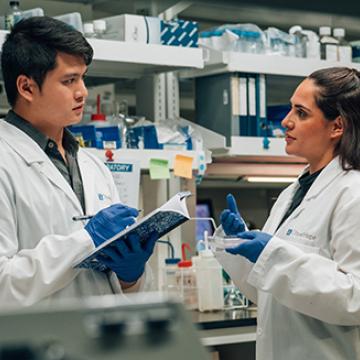 Two scientists in lab coats reviewing data, their expressions focused and engaged.
