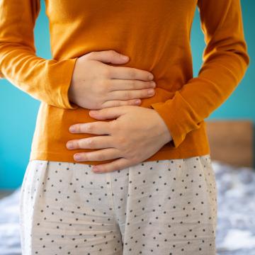 A young woman is having pain in her stomach and holding it with both hands