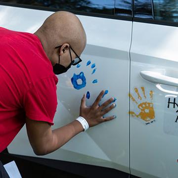 People place colorful handprints on a car at City of Hope