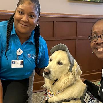Image of Oliver, the golden therapy dog, with two women
