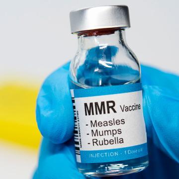 image of a measles, mumps and rubella vaccine bottle held in a blue gloved hand