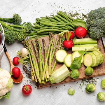 image of a variety of fresh green vegetables along with a few white and red vegetables scattered about