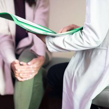 image showing a doctor in a white coat talking with a patient while holding a green file