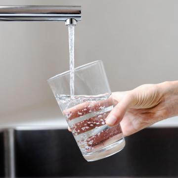 close up image of a person filling a glass of water from the tap