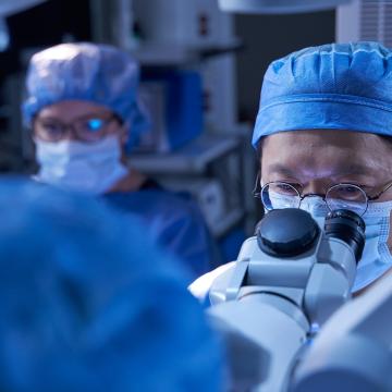 Doctors in operating room wear scrubs and face masks