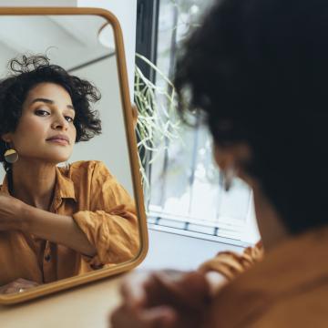 image of a woman with curly hair looking at herself in a mirror