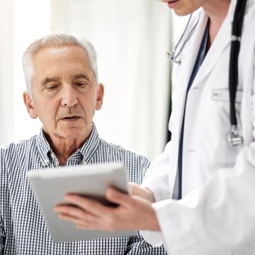 Doctor sharing electronic test results with patient using a tablet at a clinic.