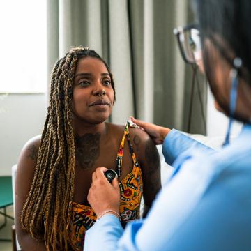 central image of a black woman with a doctor in the foreground
