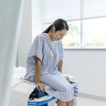 image of a woman in a hospital gown sitting on the edge of an examination table