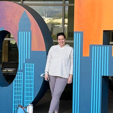Young woman standing a smiling next to HOPE letters
