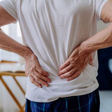 Man standing and clutching his lower back in pain