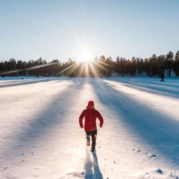 person in winter wear running through a field of snow