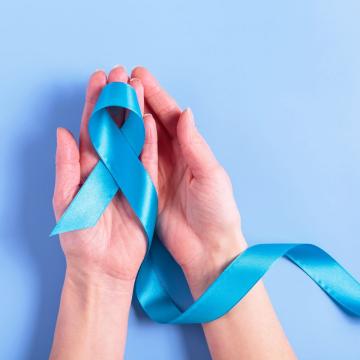Female hands cupping a blue cancer ribbon