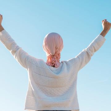 Cancer patient celebrating remission with arms in the air