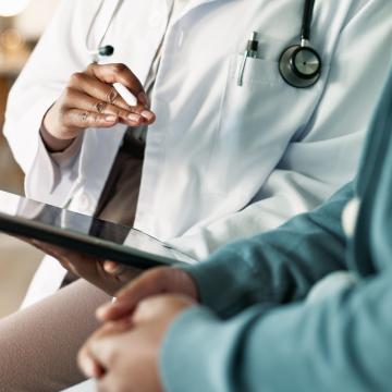 Physician reviewing information on a tablet with a patient