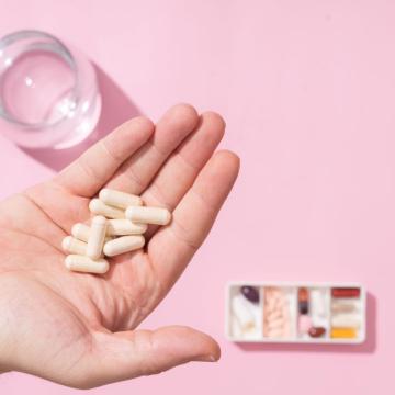 Person holding several pancreatic enzyme supplements in their hand