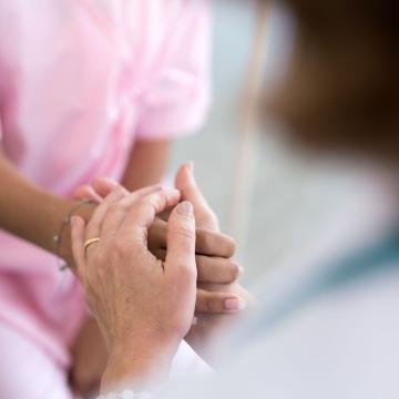 Caretaker holding the hand of a cancer patient
