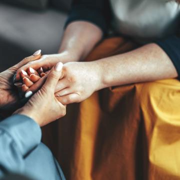 Two women holding both hands in a comforting way