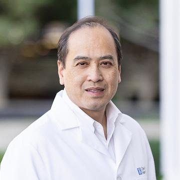 Binh Trinh, M.D., Ph.D., wearing a white coat outdoors