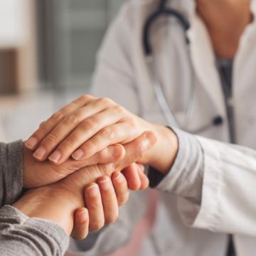 Physician comforting patient, holding their hand