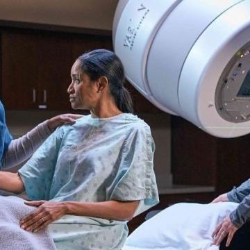 Patient about to undergo radiation imaging, holding nurse's hand