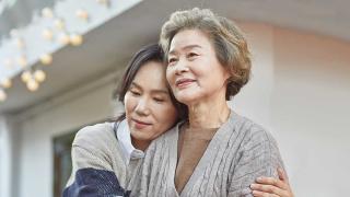Mother and daughter hugging in front of their house